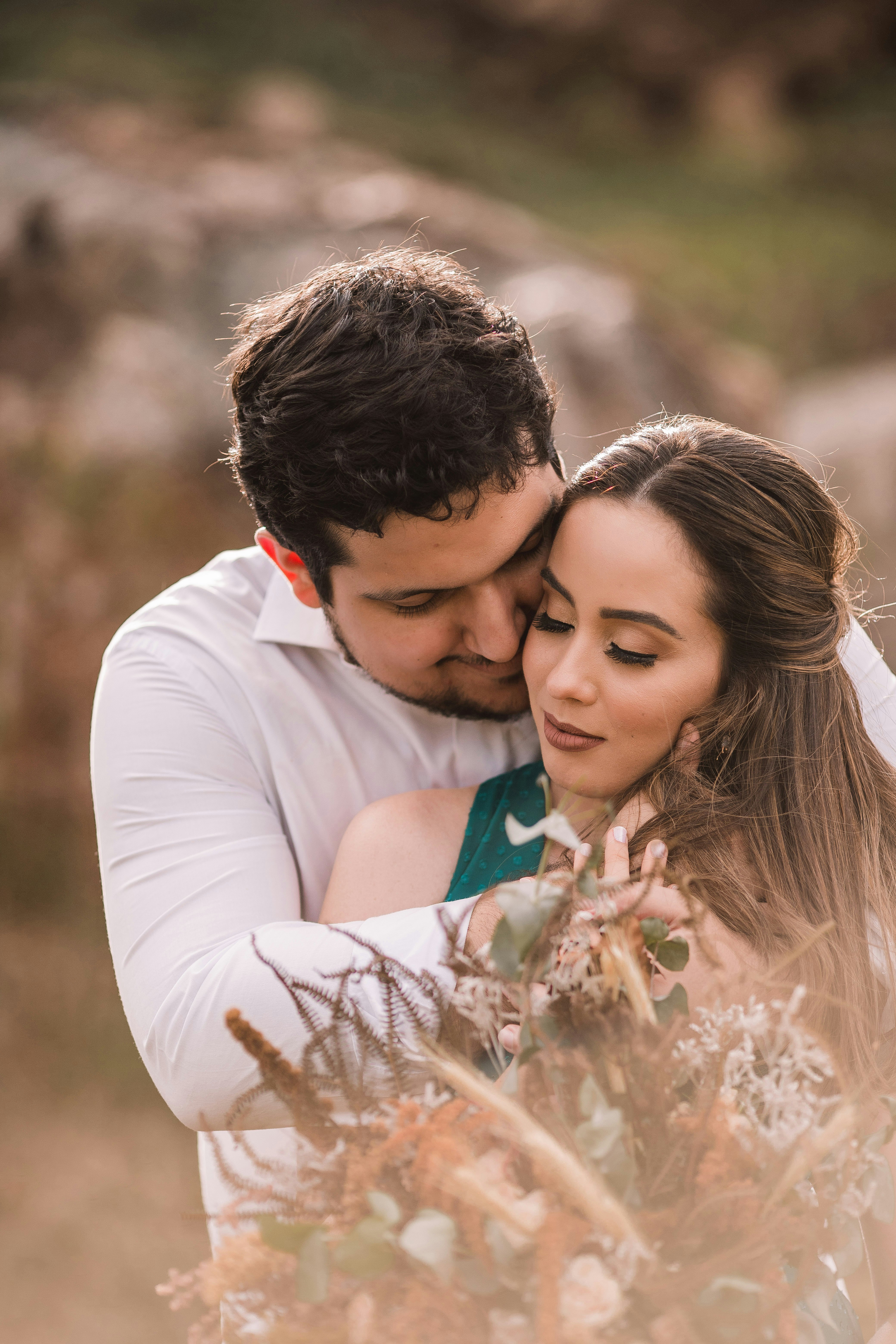 man in white long sleeve shirt kissing woman in green sleeveless shirt